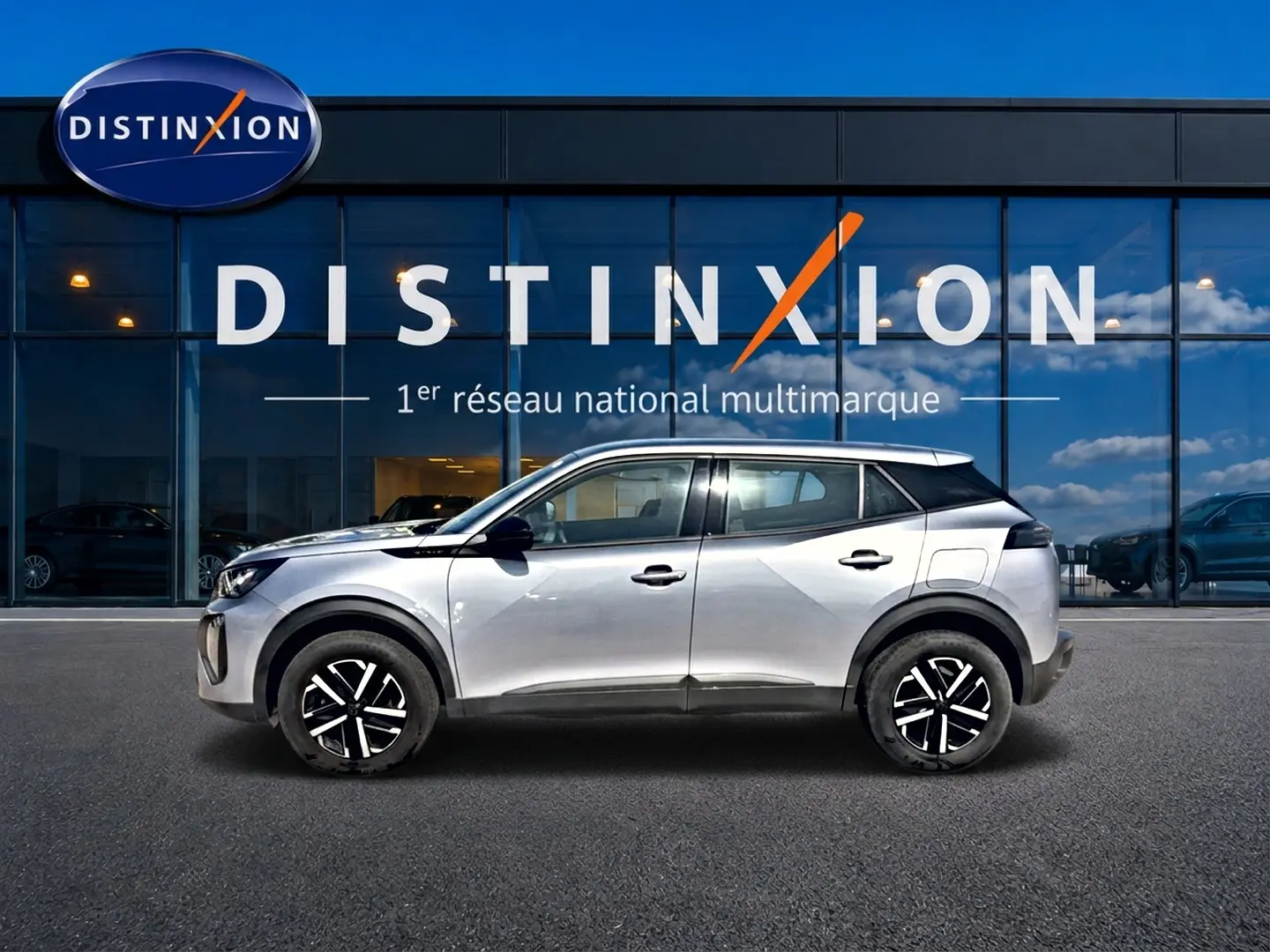 Vue de profil côté gauche d'un Peugeot 2008 gris 2025 avec jantes noires et toit blanc devant une vitrine Distinxion.