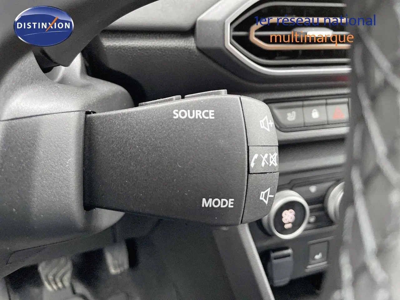 Gros plan sur la commande audio au volant du Dacia Jogger 2024, intérieur noir avec détails des boutons source et mode.