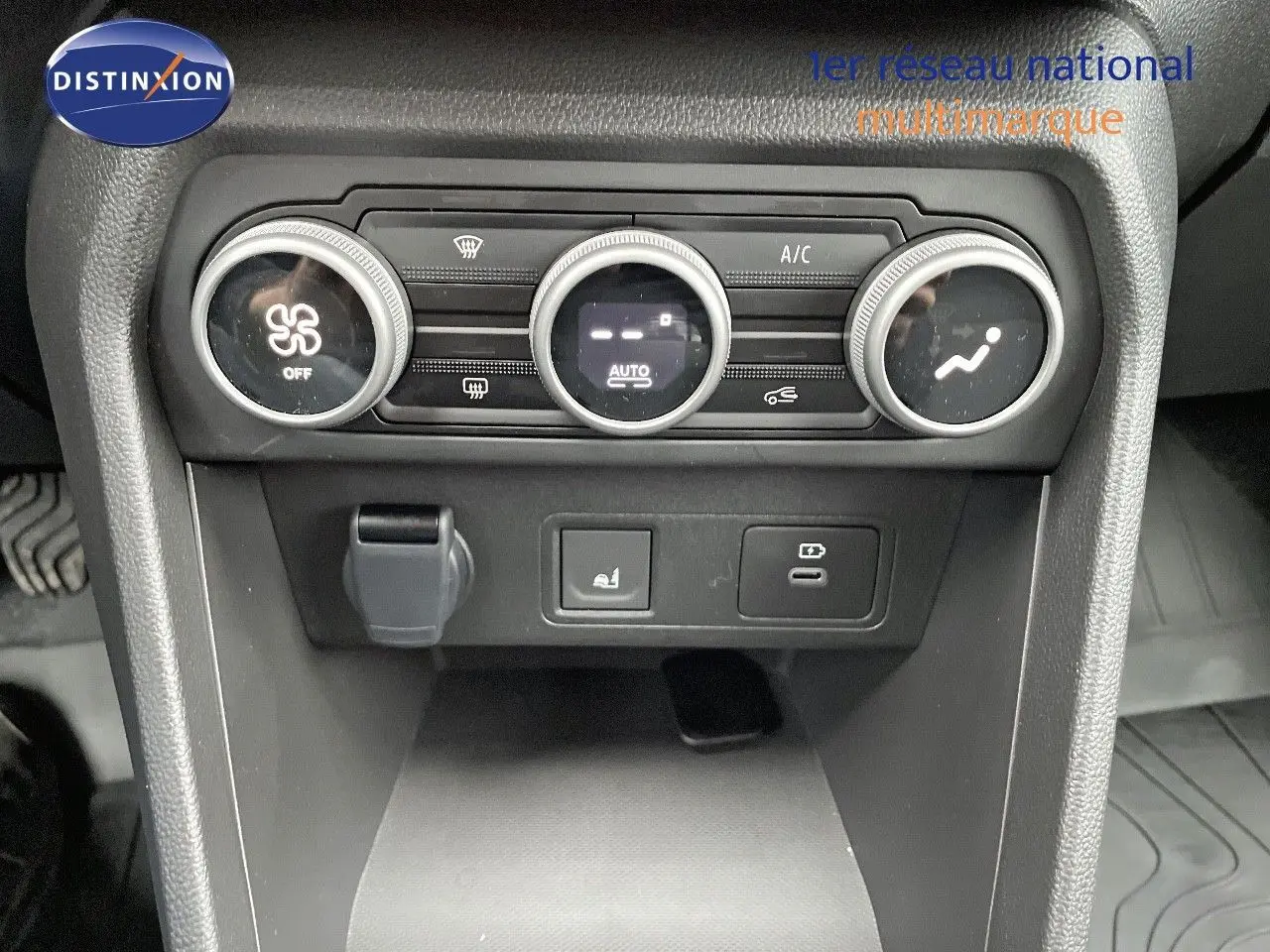 Vue rapprochée de la console centrale noire du Dacia Jogger 2024, avec commandes de climatisation et prises USB.