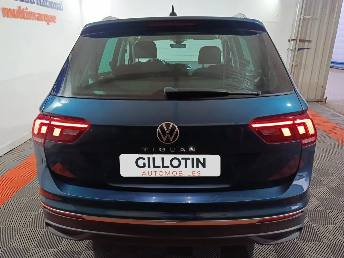 Vue arrière d'un Volkswagen Tiguan bleu 2021 avec feux arrière LED allumés dans un garage.