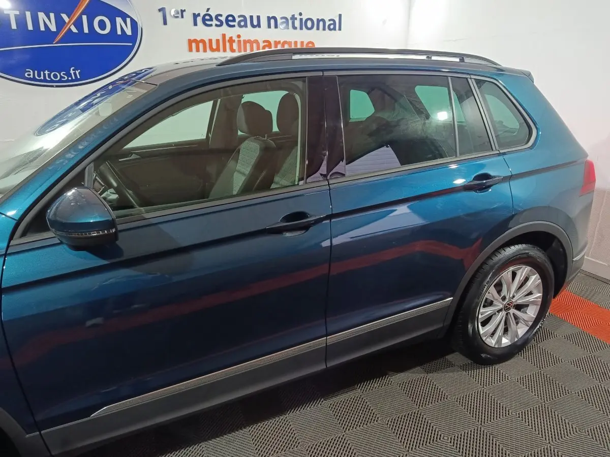 Vue latérale droite du Volkswagen Tiguan bleu 2021 avec jantes alliage et rétroviseurs intégrant clignotants.