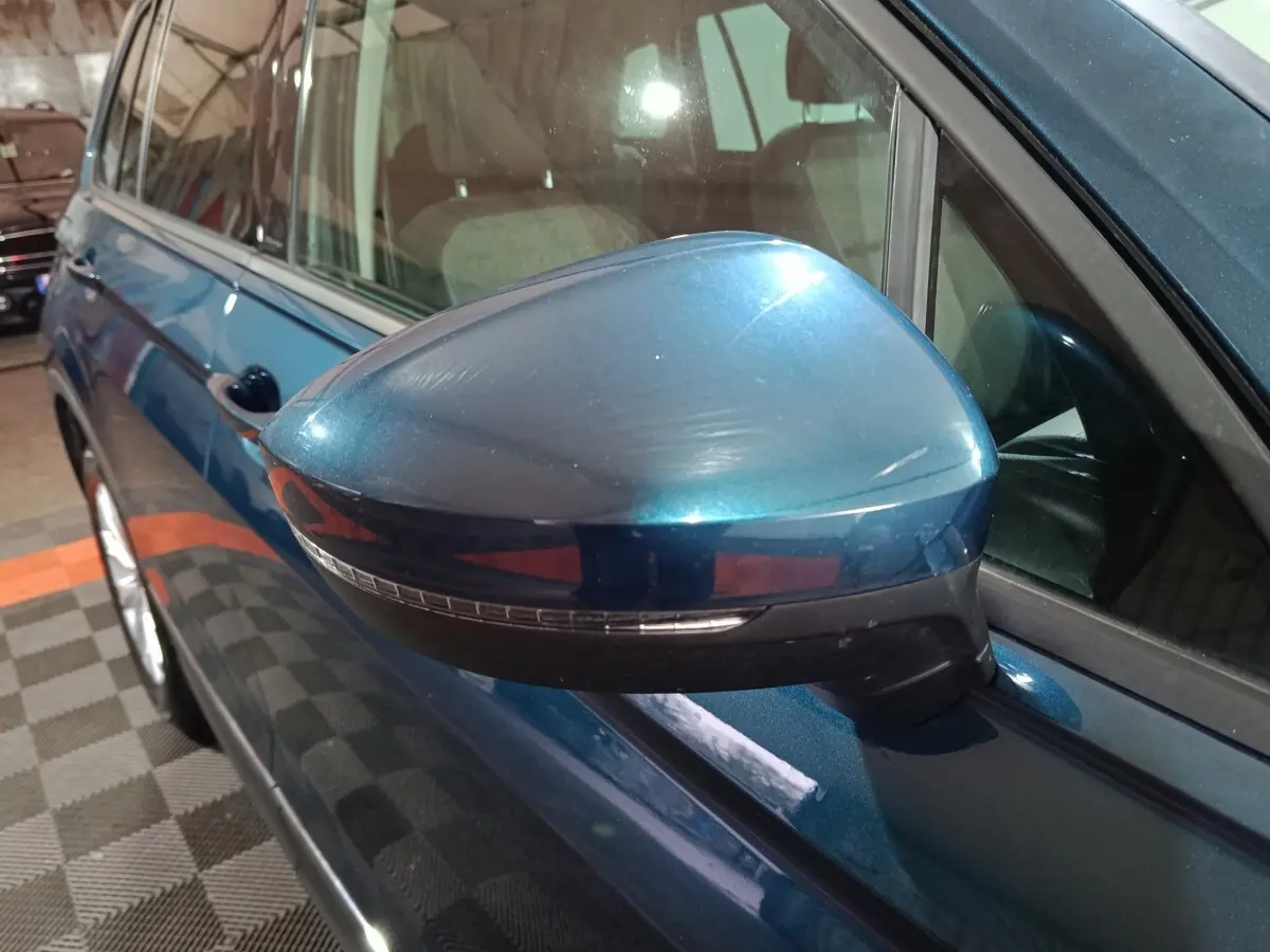 Vue rapprochée du rétroviseur côté conducteur bleu métallisé du Volkswagen Tiguan 2021, avec clignotant intégré.