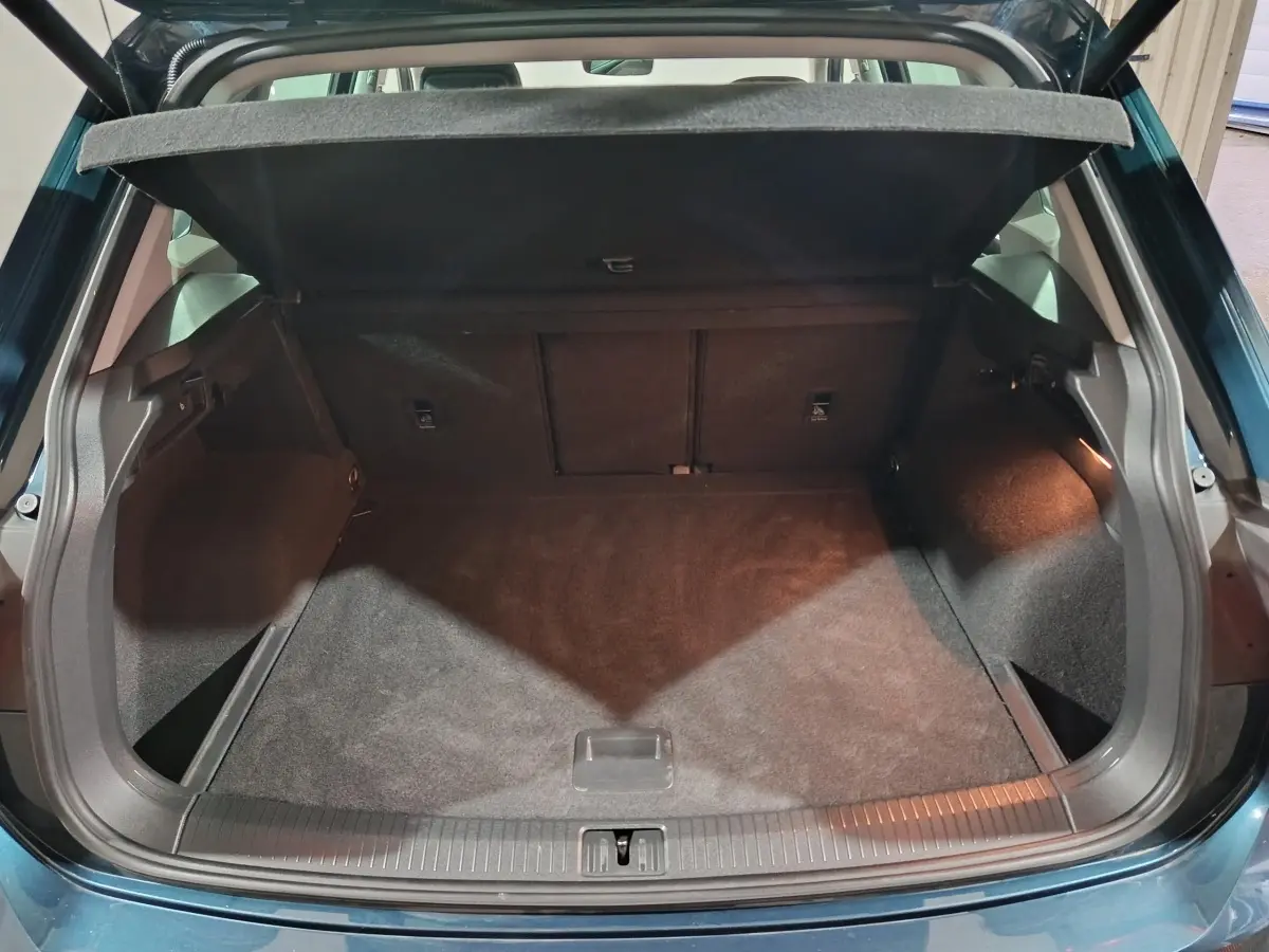 Vue arrière du coffre ouvert du Volkswagen Tiguan bleu 2021, montrant un espace de rangement propre et spacieux.