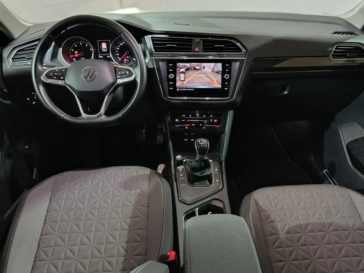 Vue intérieure avant du Volkswagen Tiguan 2021 avec volant cuir multifonctions, écran tactile et levier de vitesses manuel.