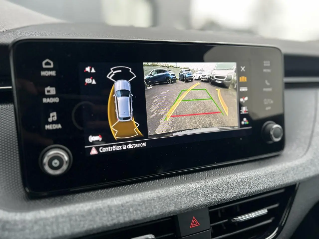 Écran central du Skoda Kamiq noir Magic montrant la caméra de recul et l'aide au stationnement en vue intérieure.