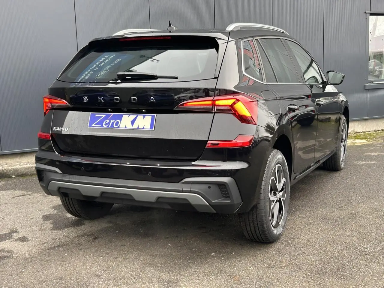 Vue 3/4 arrière droite d’un Skoda Kamiq noir Magic avec feux LED et jantes alliage 16 pouces visibles.