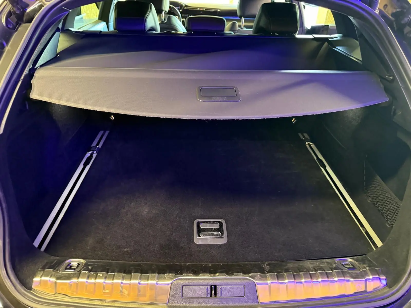 Coffre ouvert d’un Peugeot 508 SW noir, vue arrière montrant la plage arrière et le tapis de coffre noir.