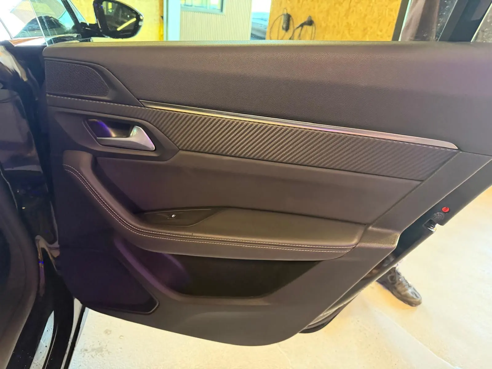 Vue rapprochée de la porte arrière gauche noire avec insert carbone et surpiqûres blanches du Peugeot 508 SW 2024.