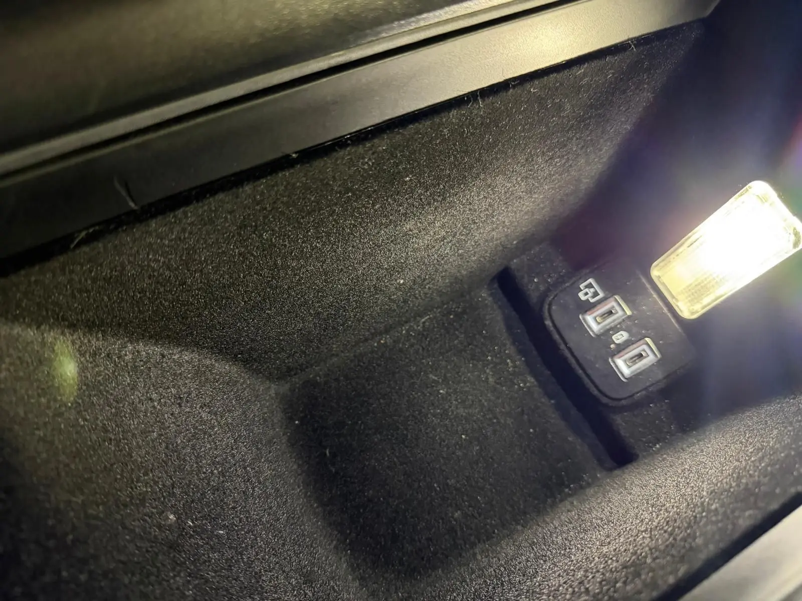 Gros plan sur le rangement central avant noir avec prises USB et éclairage intérieur dans une Peugeot 508 SW 2024.