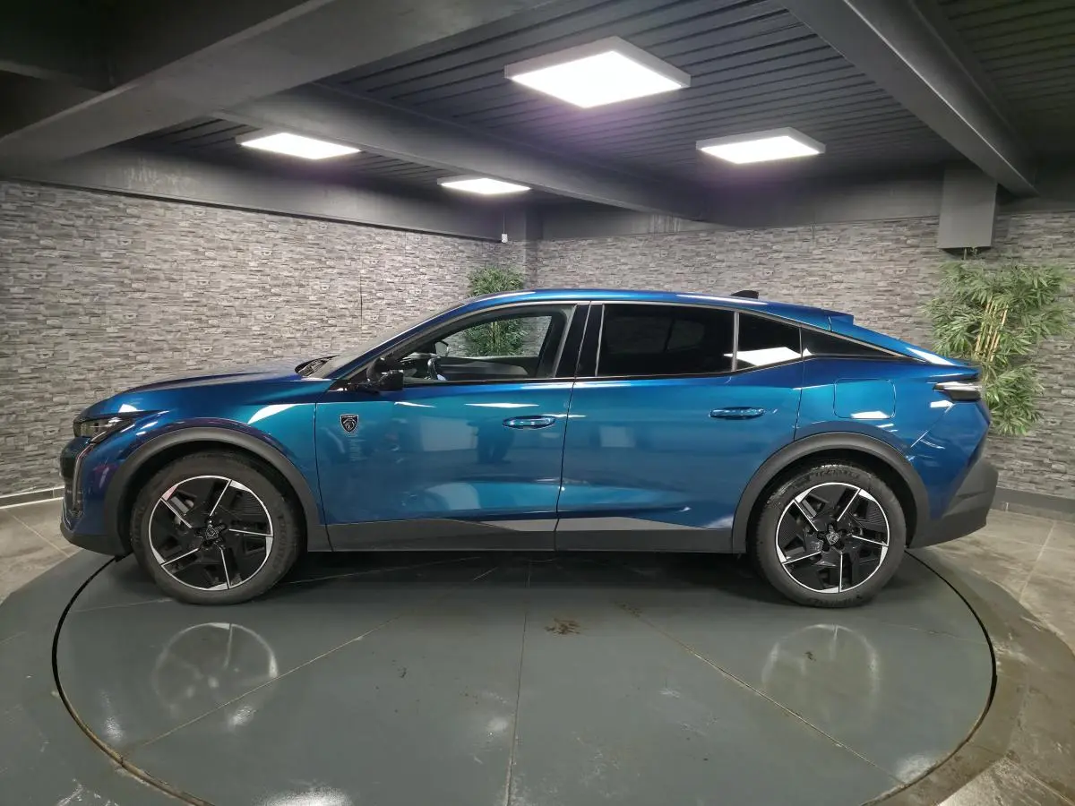 Profil droit d'une Peugeot 408 hybride rechargeable bleu métallisé, avec jantes alliage 19 pouces et vitres teintées.