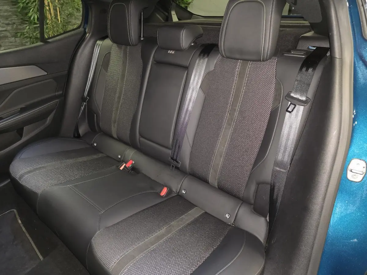 Vue latérale droite de la banquette arrière en tissu et cuir noir de la Peugeot 408 bleu métallisé 2024.