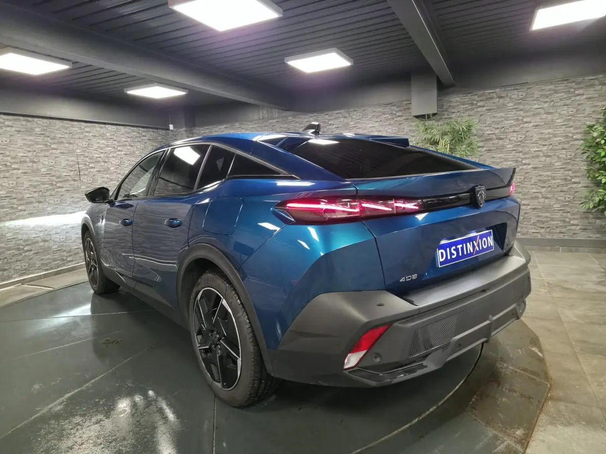 Vue 3/4 arrière droite d'une Peugeot 408 hybride rechargeable bleu métallisé avec feux arrière LED griffés et jantes alliage 19 pouces.