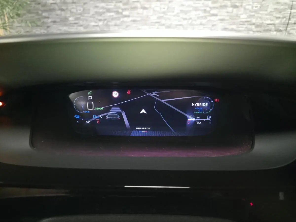 Vue rapprochée du combiné numérique 10 pouces du Peugeot 408 hybride, affichant navigation et état batterie.