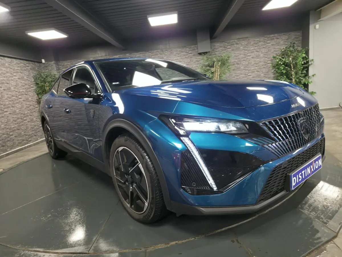Peugeot 408 hybride rechargeable bleu, vue 3/4 avant droit, avec calandre distinctive et feux LED griffés.