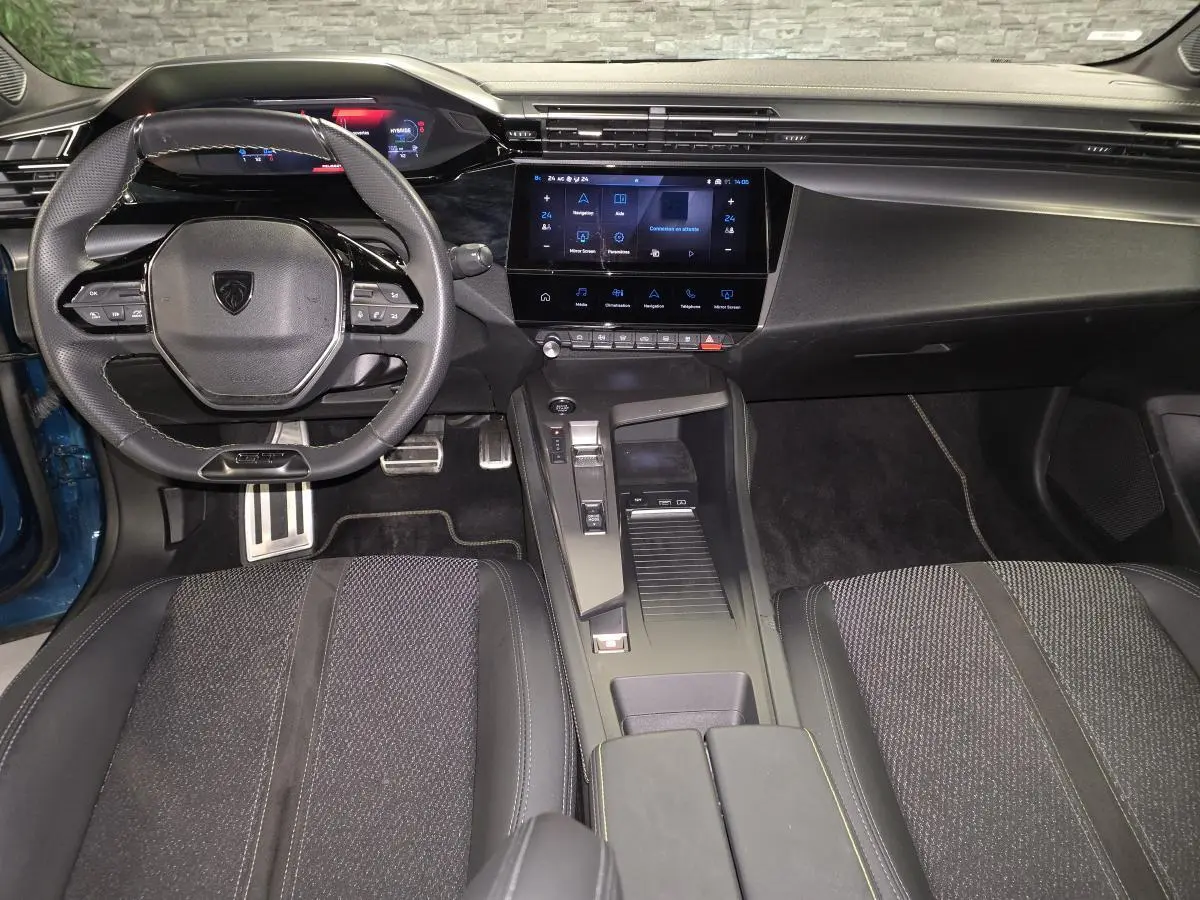 Intérieur avant du Peugeot 408 2024 bleu, vue centrée sur le volant, tableau de bord numérique et console centrale moderne.