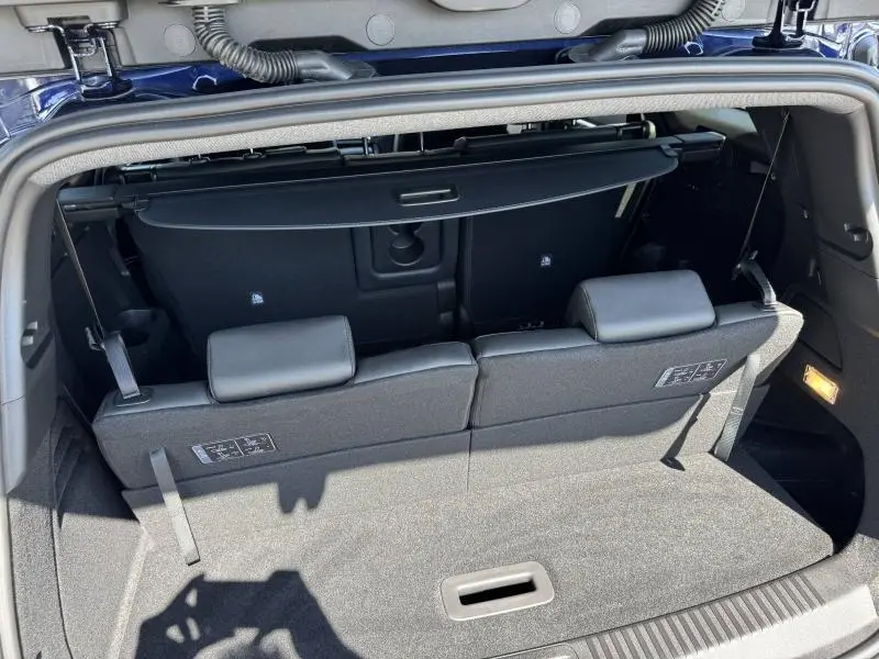 Coffre ouvert vu de l'arrière du Renault Espace Bleu Nocturne 2025, montrant la banquette 3e rangée et cache-bagages.