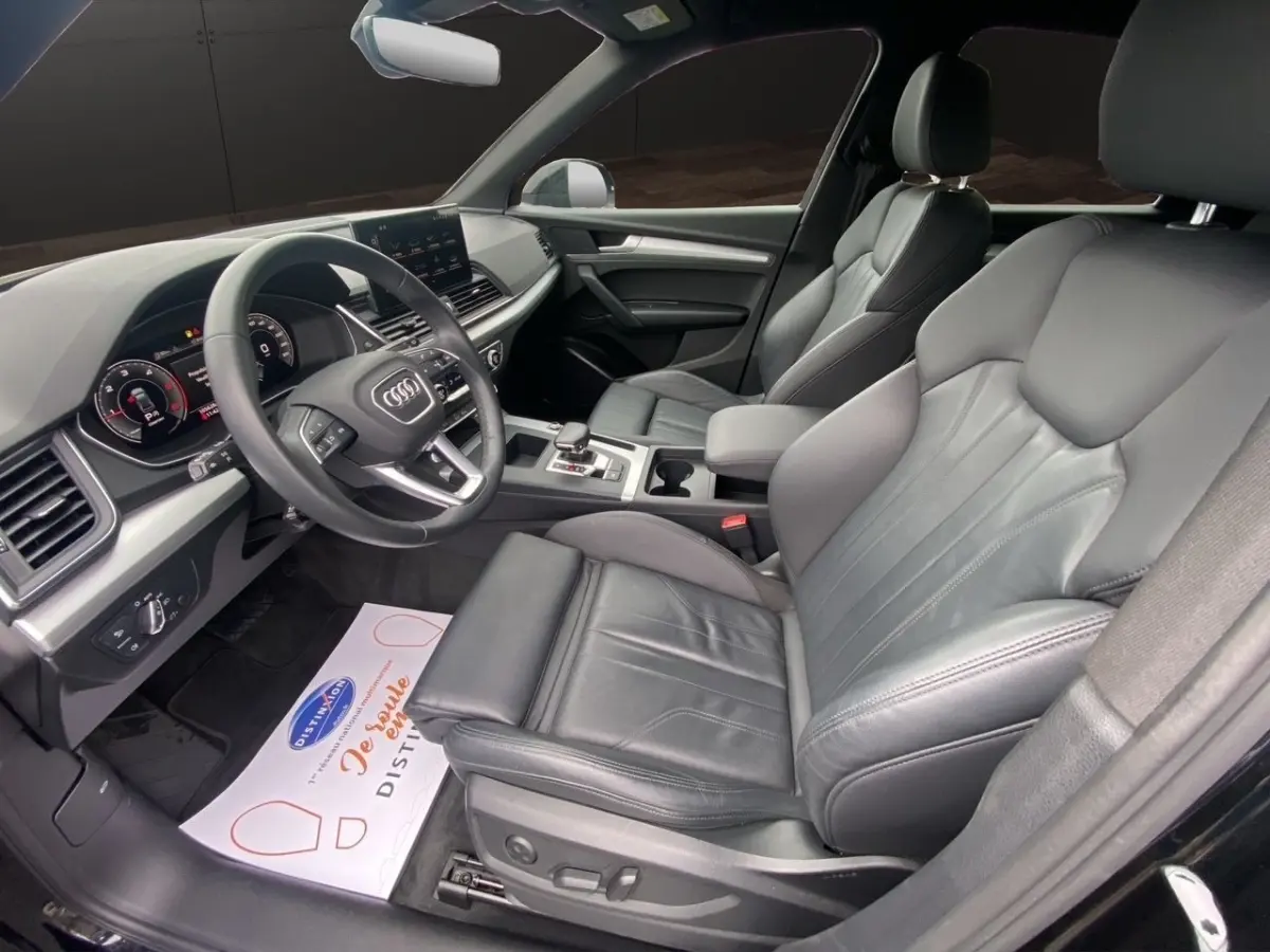 Vue intérieure côté conducteur de l'Audi Q5 35 TDI 2022 avec sièges cuir noirs et tableau de bord digital.