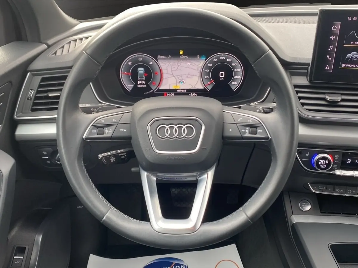 Vue intérieure centrée sur le volant cuir et le combiné d'instruments numérique de l'Audi Q5 35 TDI noir 2022.