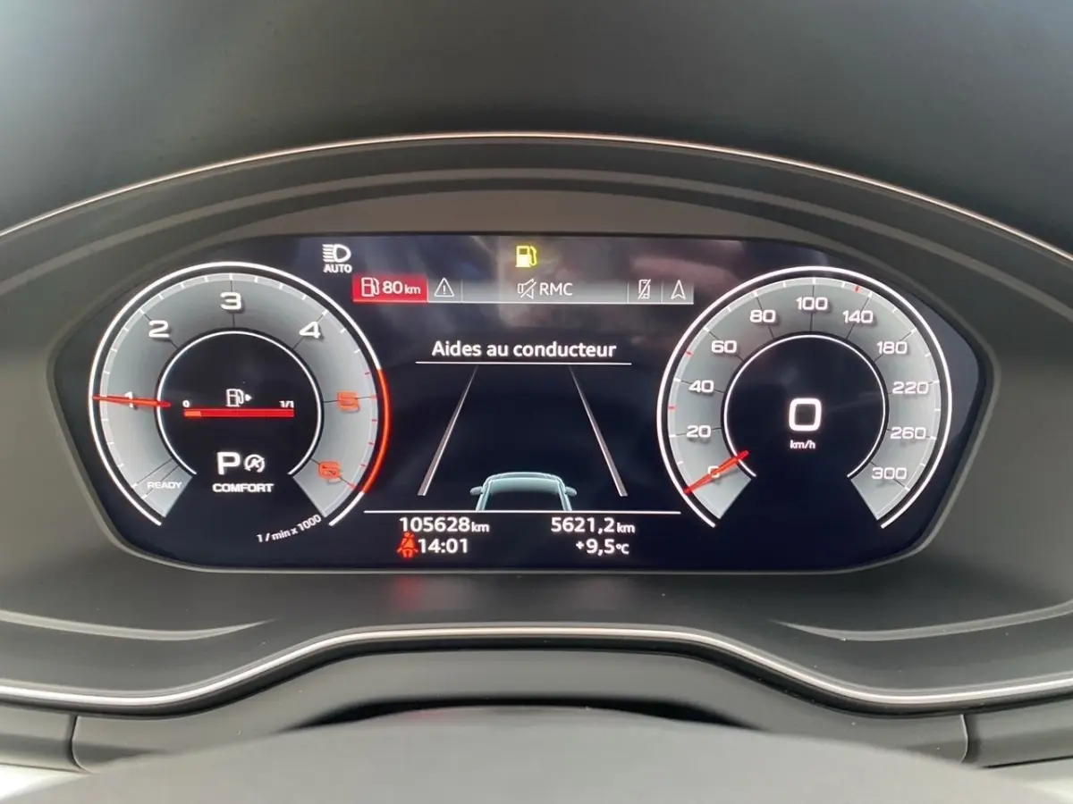 Gros plan sur le combiné d'instruments numérique de l'Audi Q5 noir, affichant les aides au conducteur et la vitesse à 0 km/h.