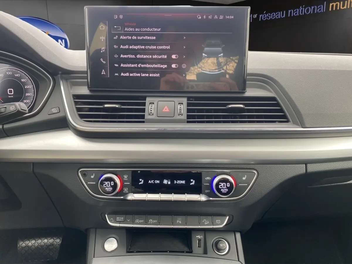 Vue intérieure du tableau de bord de l'Audi Q5 35 TDI noir, avec écran tactile central et commandes climatisation 3 zones.