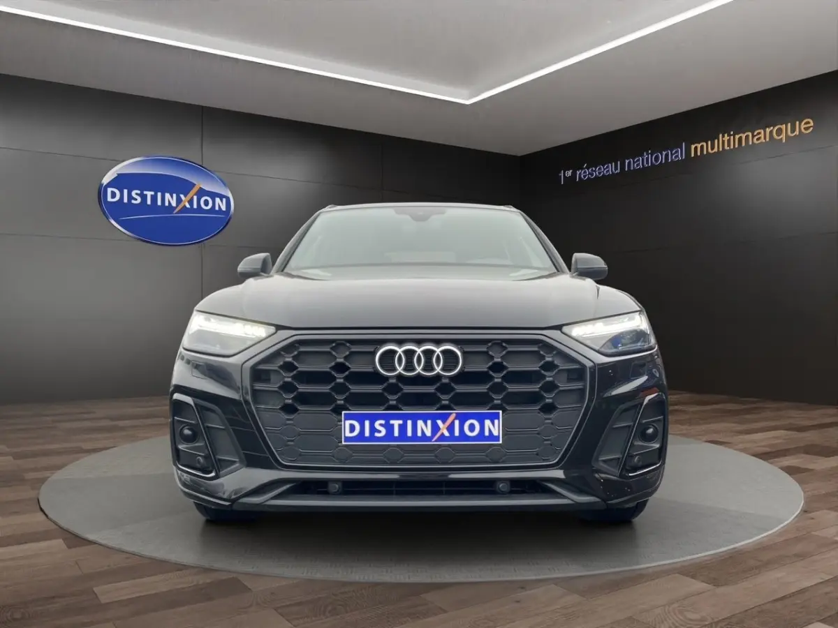 Audi Q5 35 TDI S Line noir vue de face, avec calandre hexagonale et phares LED allumés en showroom.