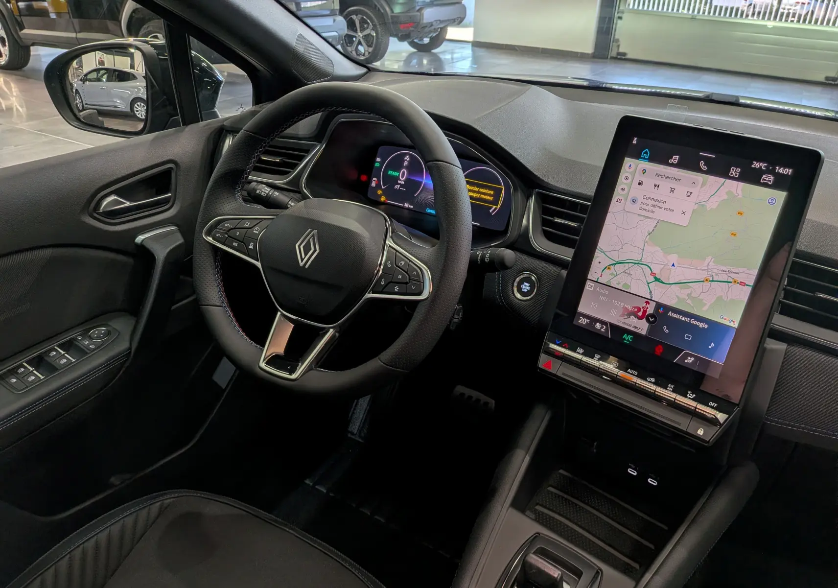 Vue intérieure du tableau de bord du Renault Captur E-TECH 2026, avec volant multifonction et écran tactile central vertical.