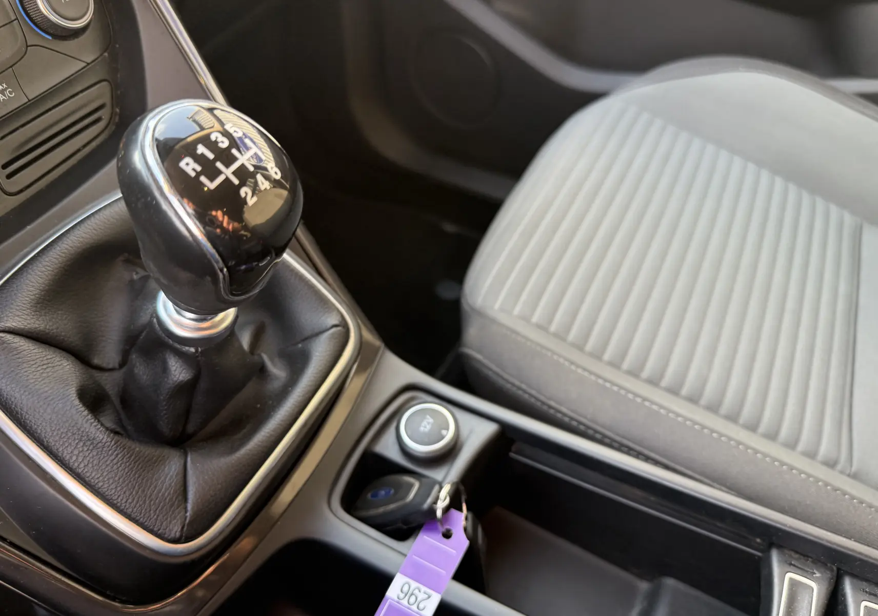 Gros plan sur la boîte manuelle noire et la sellerie tissu gris clair côté passager du Ford C-MAX vert 2018.