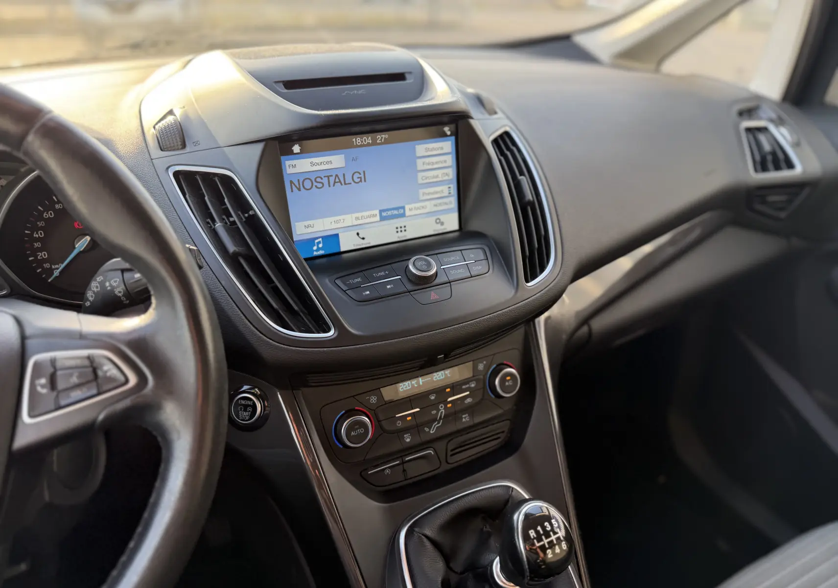 Vue intérieure du tableau de bord et console centrale d'une Ford C-MAX 2018, avec écran tactile et levier de vitesses manuel.