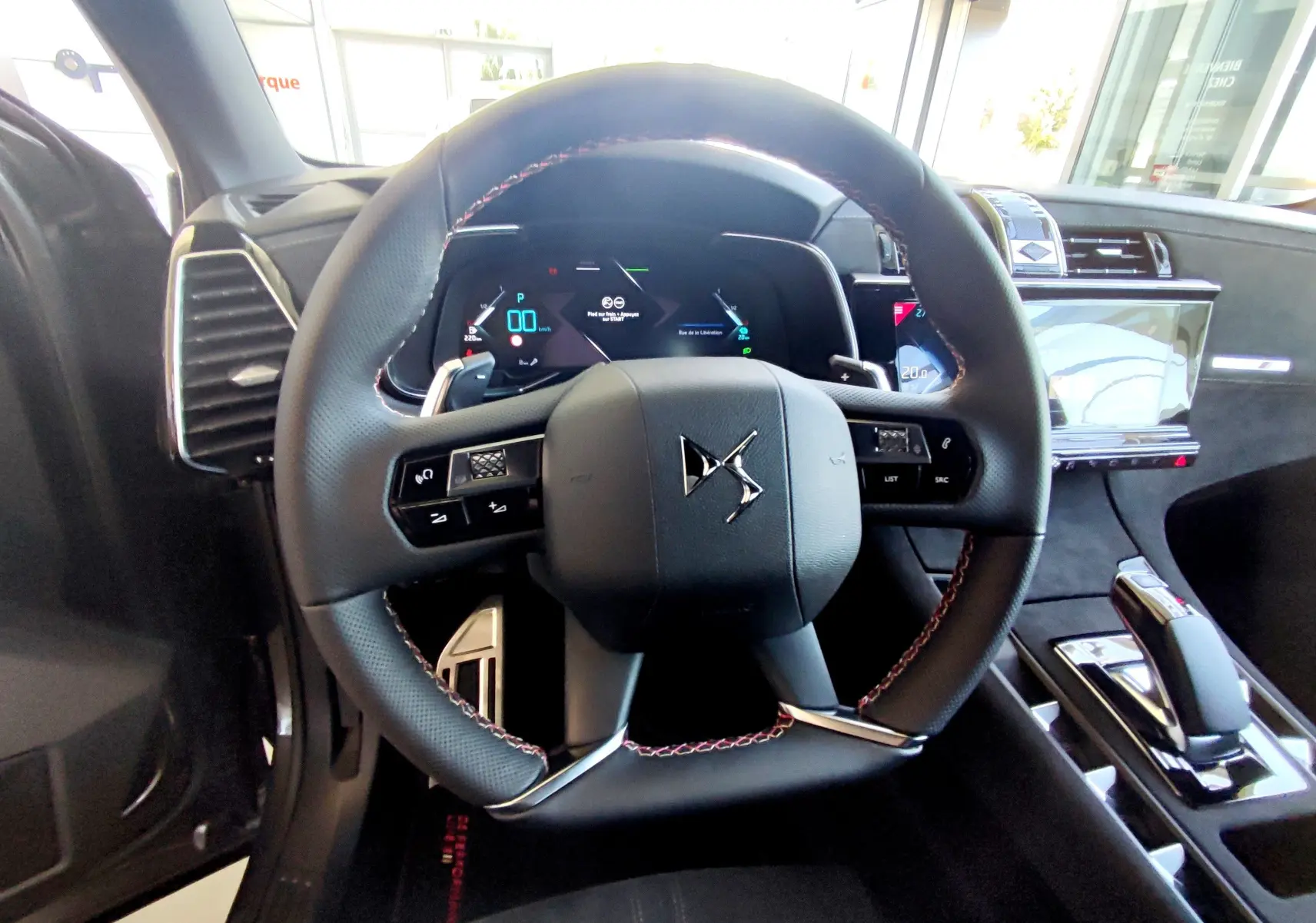 Vue intérieure centrée sur le volant DS du DS7 Crossback gris 2022, avec tableau de bord numérique et console moderne.