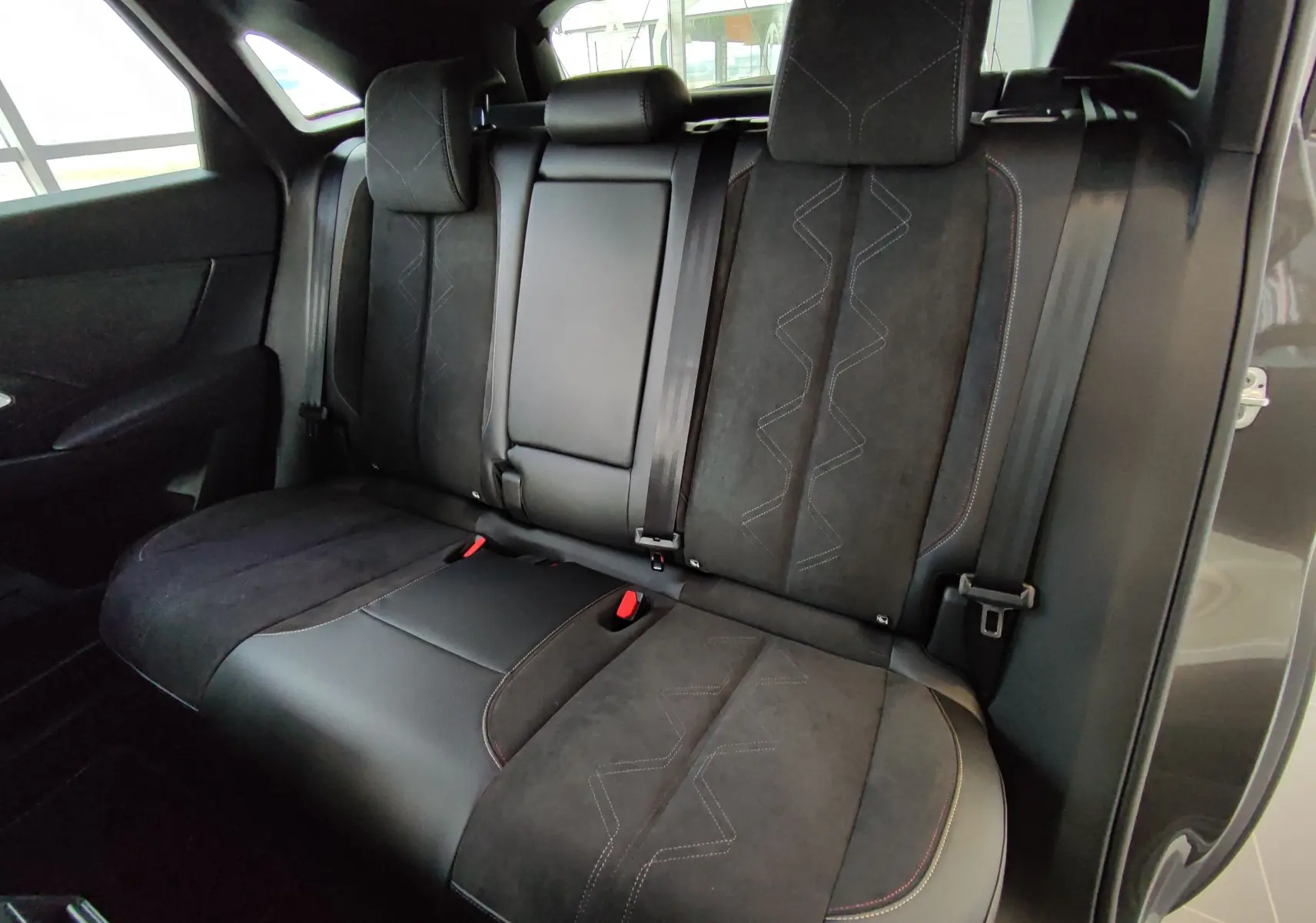 Vue intérieure arrière du DS7 Crossback gris 2022, montrant les sièges arrière en cuir et alcantara avec surpiqûres décoratives.