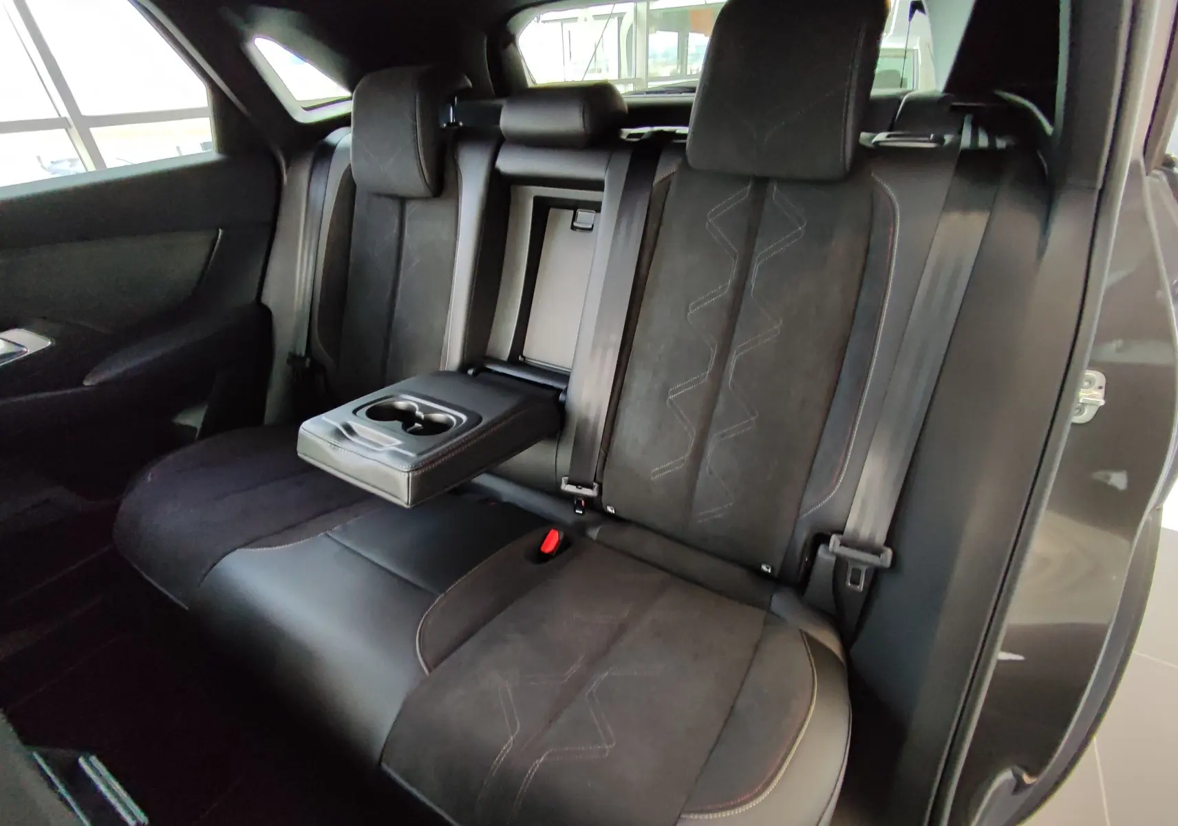 Vue intérieure sur les sièges arrière noirs du DS7 Crossback E-TENSE 2022 avec accoudoir central et porte-gobelets déployé.
