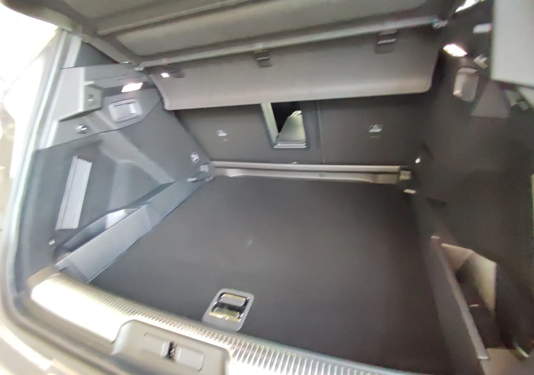 Coffre spacieux du DS7 Crossback gris, vue intérieure arrière avec banquette rabattue et finition noire.