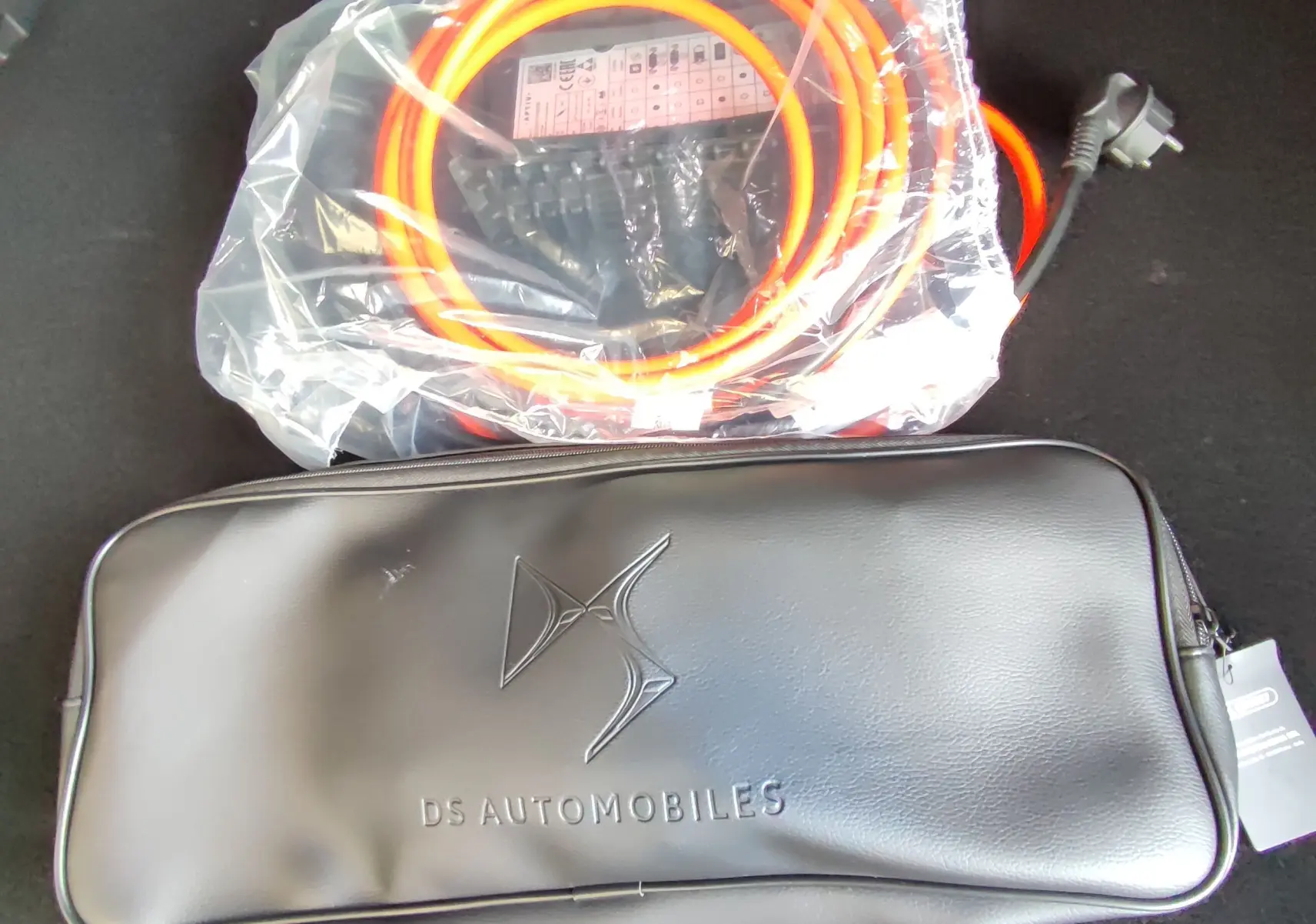 Câble de recharge orange et sac noir DS Automobiles dans le coffre d'un DS7 Crossback hybride gris, vue intérieure.