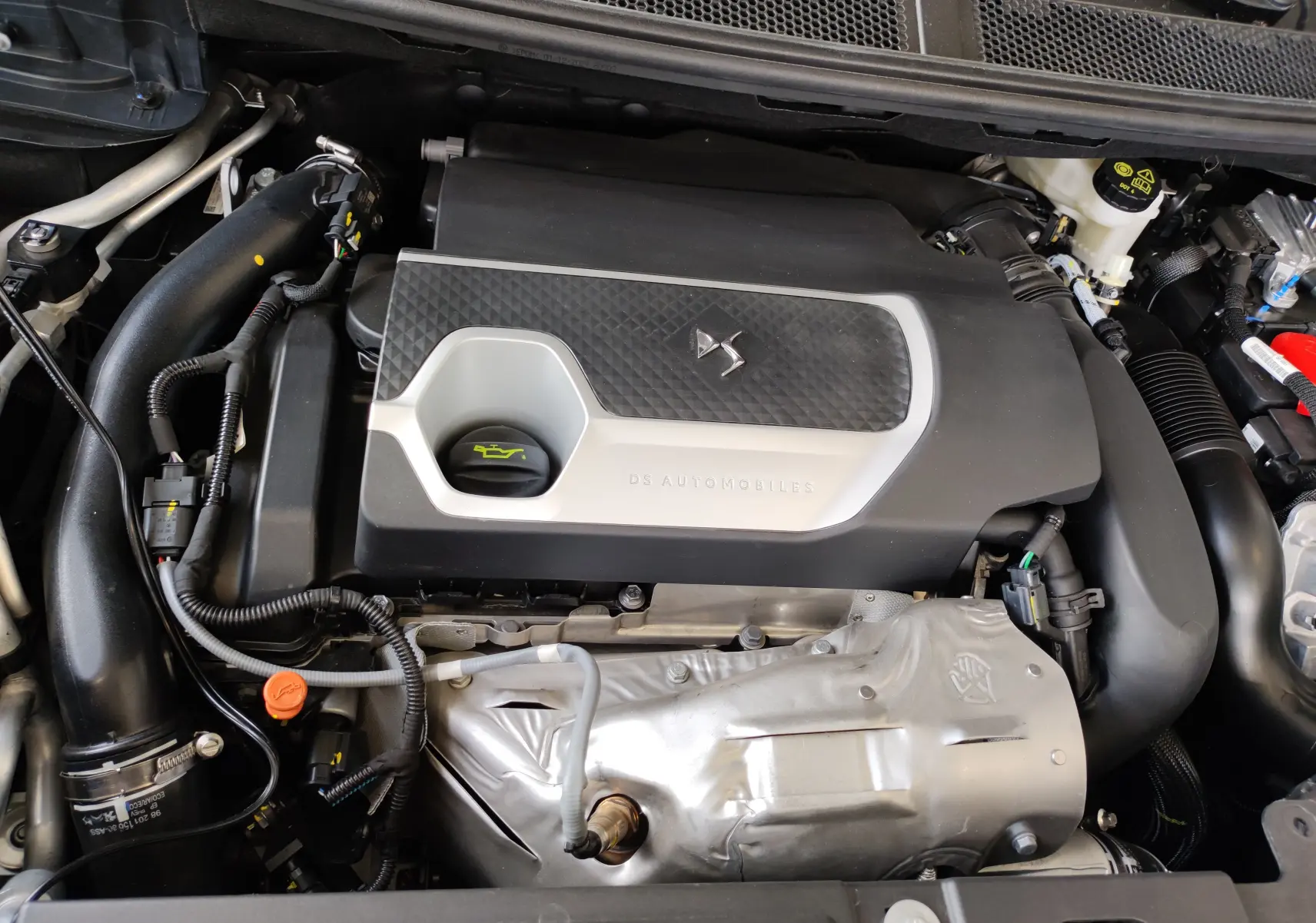 Vue rapprochée du moteur gris du DS7 Crossback E-TENSE 225ch 2022 avec logo DS et inscription DS Automobiles.