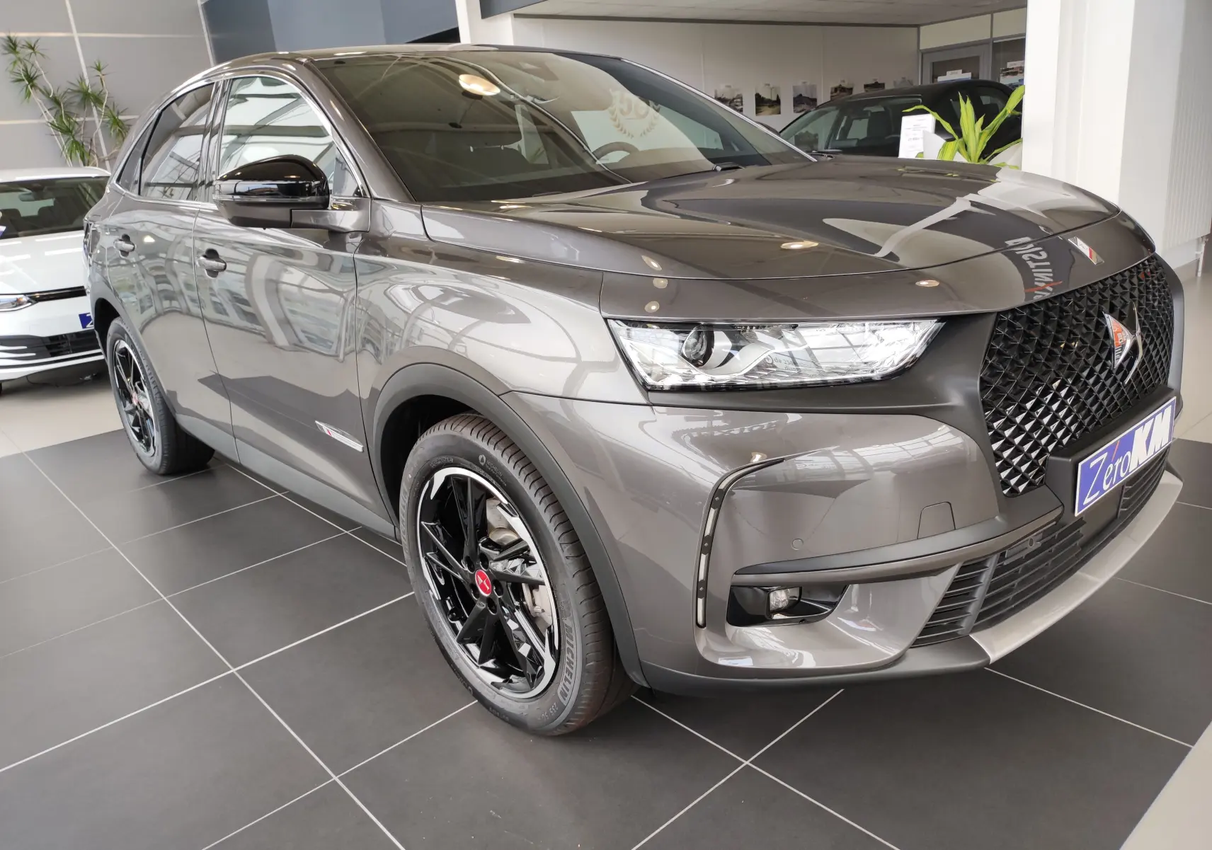 DS7 Crossback E-TENSE gris en 3/4 avant droit, avec calandre noire et jantes noires brillantes en showroom.