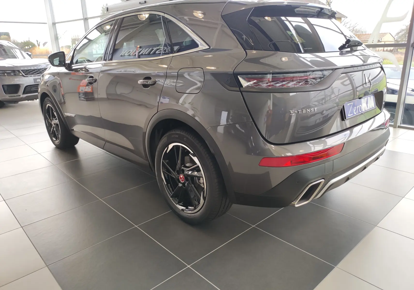 Vue 3/4 arrière droite du DS7 Crossback E-TENSE gris 2022 avec jantes noires et feux arrière LED distinctifs.