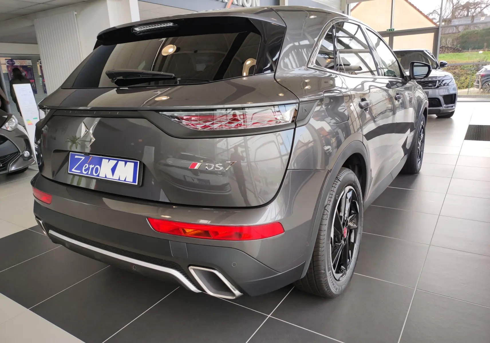 Vue 3/4 arrière droite du DS7 Crossback E-TENSE gris 2022 avec feux arrière LED et jantes noires en concession.