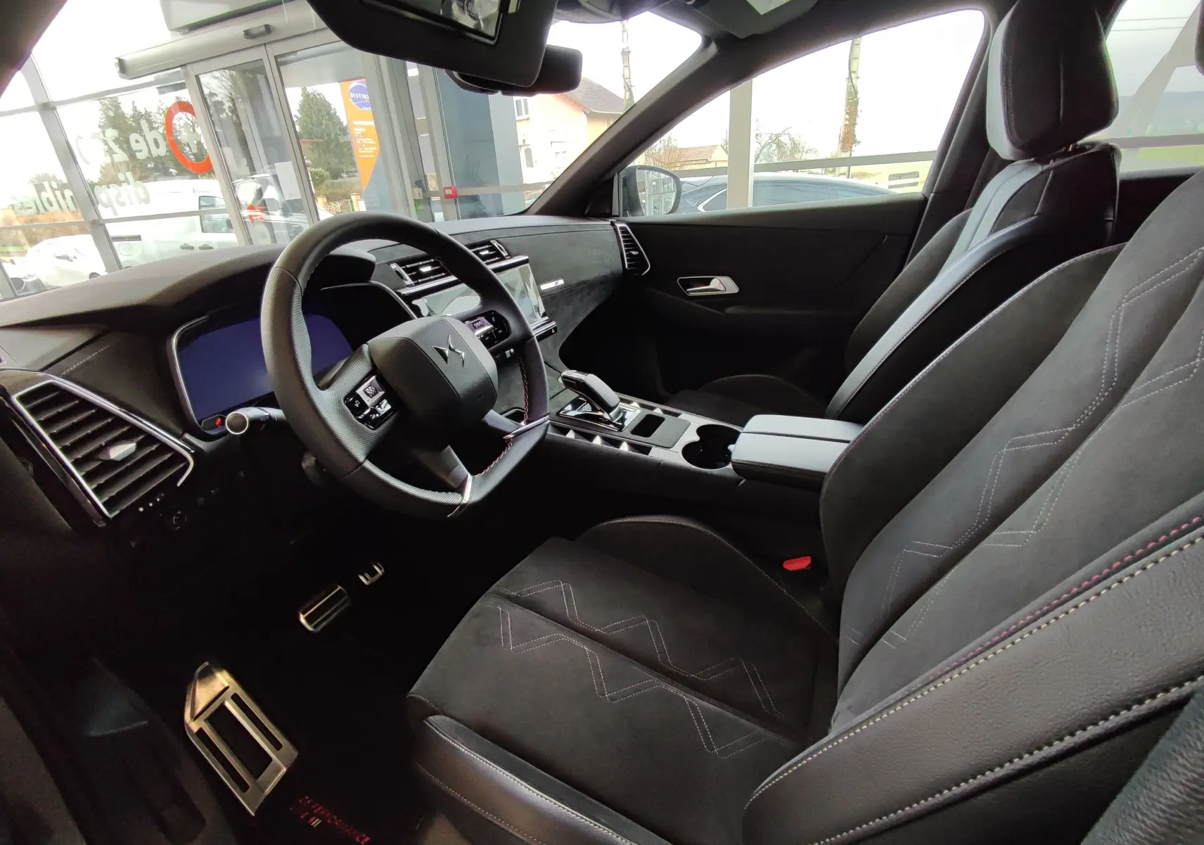 Vue intérieure côté conducteur du DS7 Crossback gris 2022, montrant le volant, les sièges en cuir et la console centrale moderne.