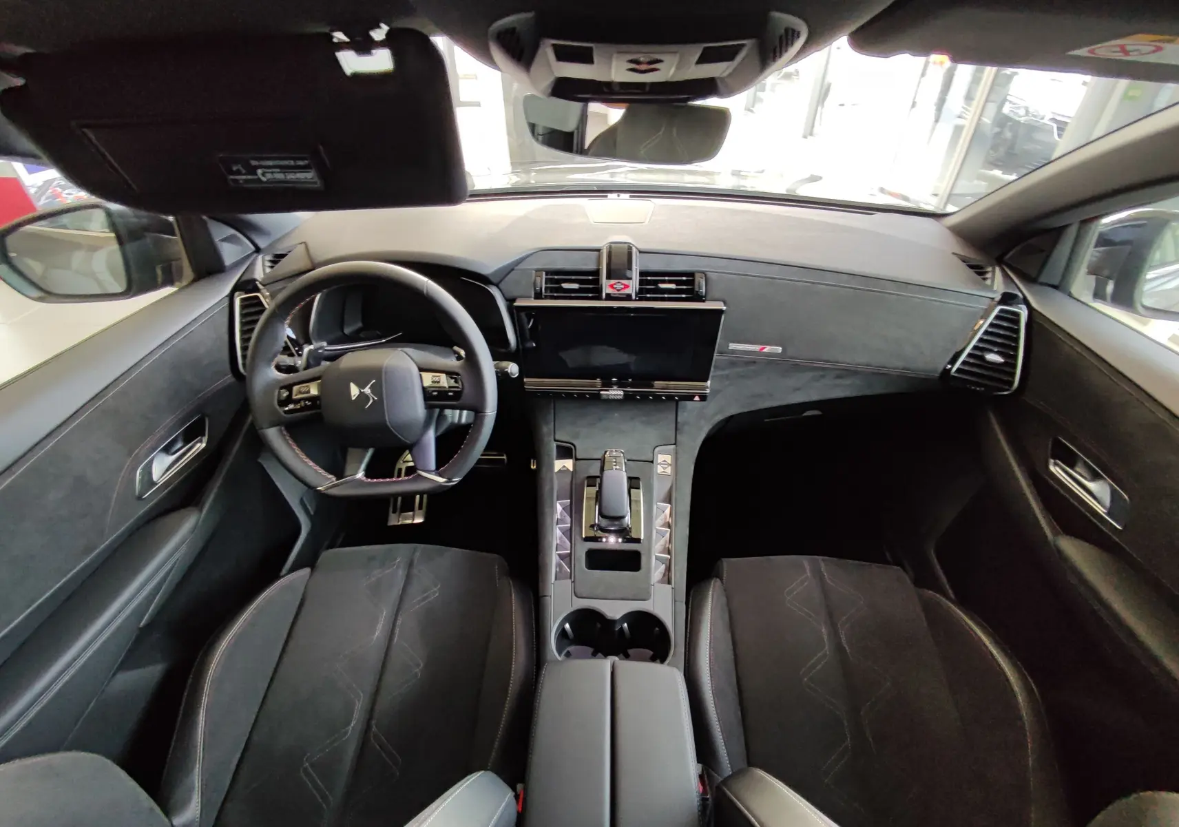 Vue intérieure avant du DS7 Crossback E-TENSE 225ch gris, avec tableau de bord moderne et volant multifonction.