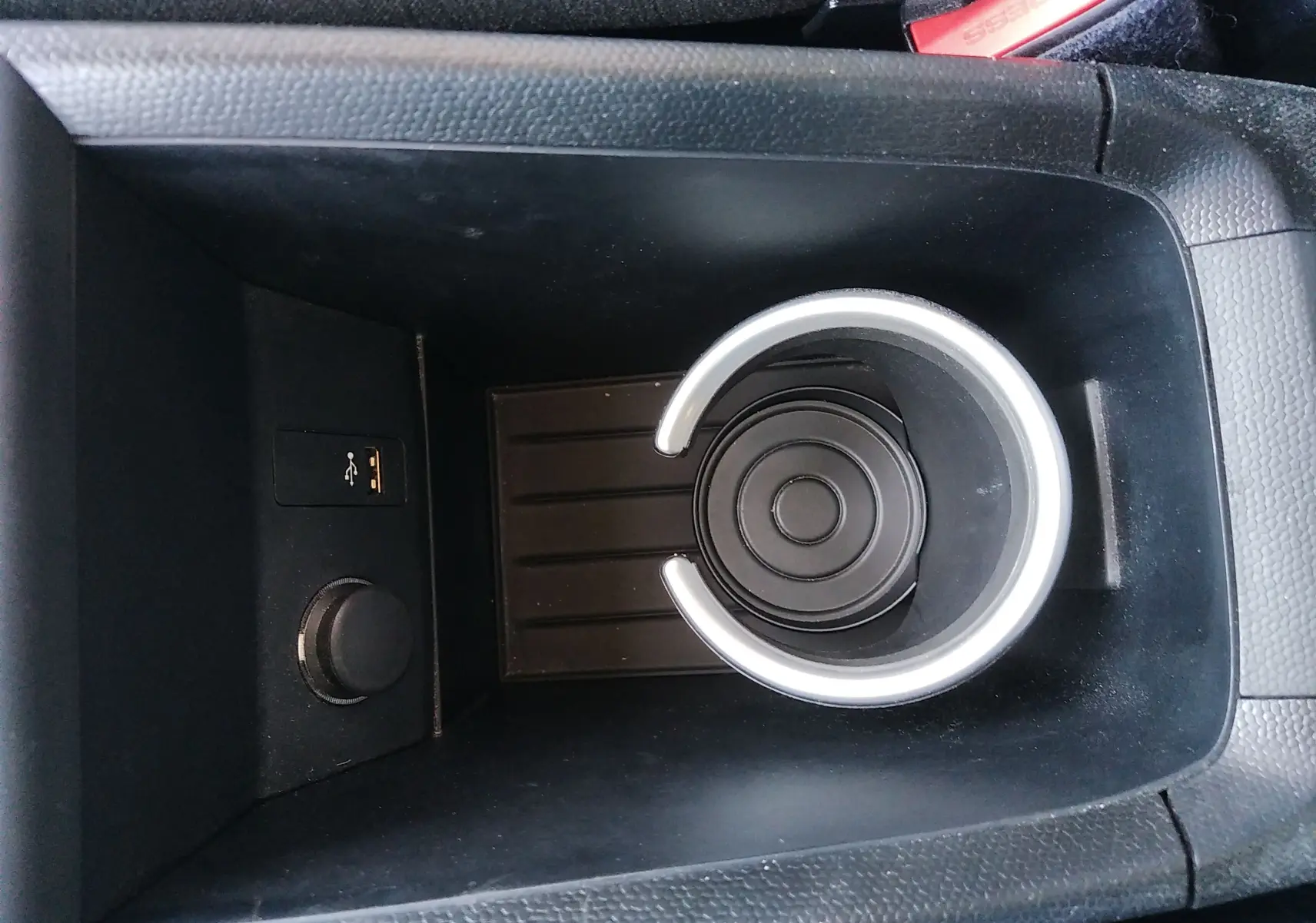 Gros plan sur le porte-gobelet noir et la prise USB dans la console centrale d'une BMW i3 bleu électrique 2022.