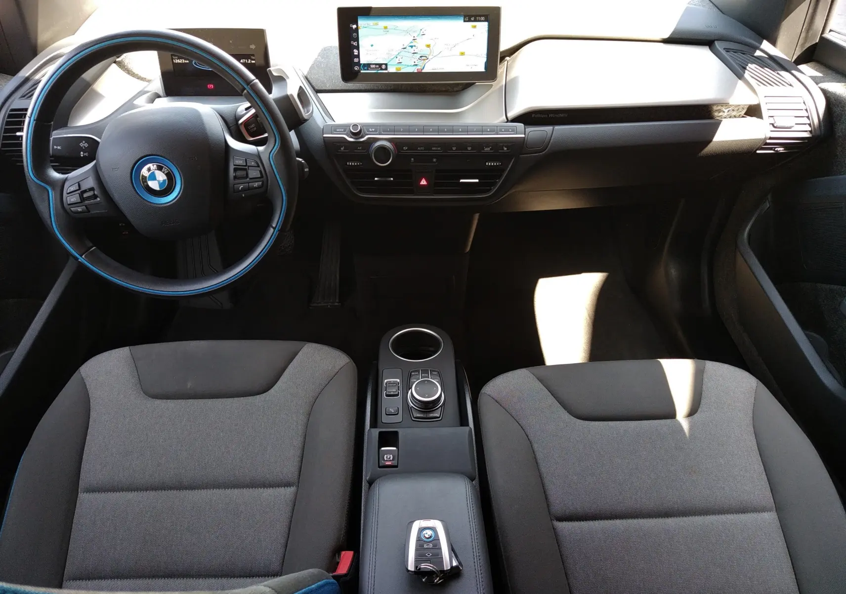 Intérieur de la BMW i3 bleu 2022 en vue plongeante, tableau de bord avec écran GPS et volant au cerclage bleu.