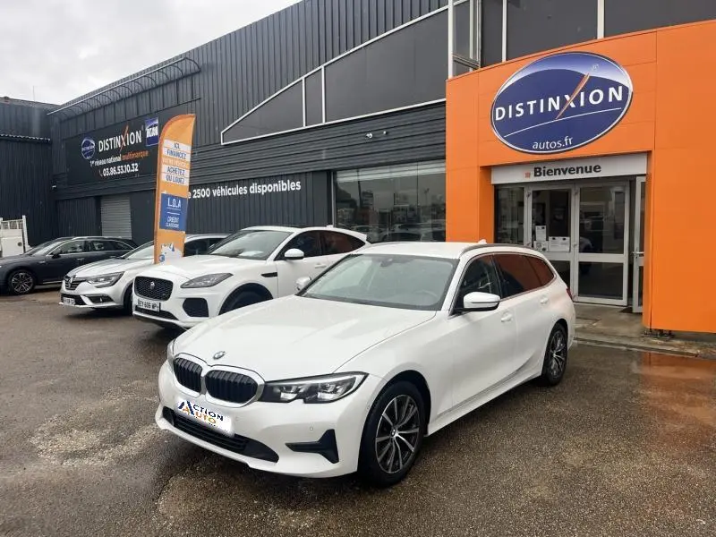 BMW Série 3 316dA blanche vue en 3/4 avant droit devant un concessionnaire Distinxion