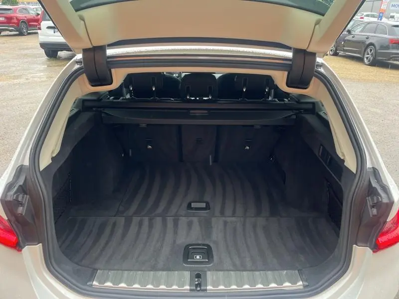 Coffre ouvert vu de l'arrière d'une BMW Série 3 316dA Business Design Alpinweiss, intérieur noir spacieux et propre.