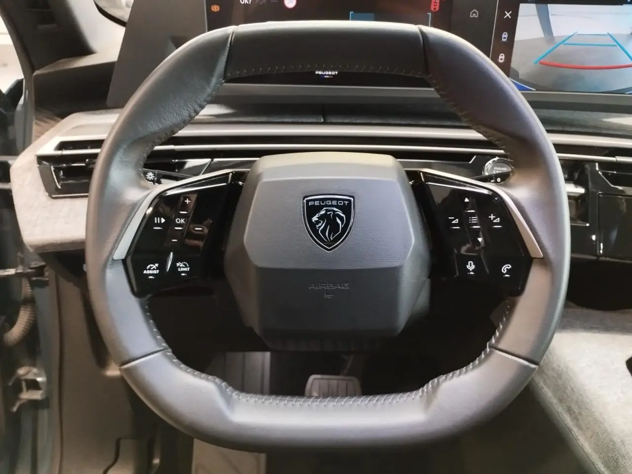 Vue rapprochée du volant compact en cuir noir du Peugeot 5008 2025 avec commandes intégrées et logo lion central.