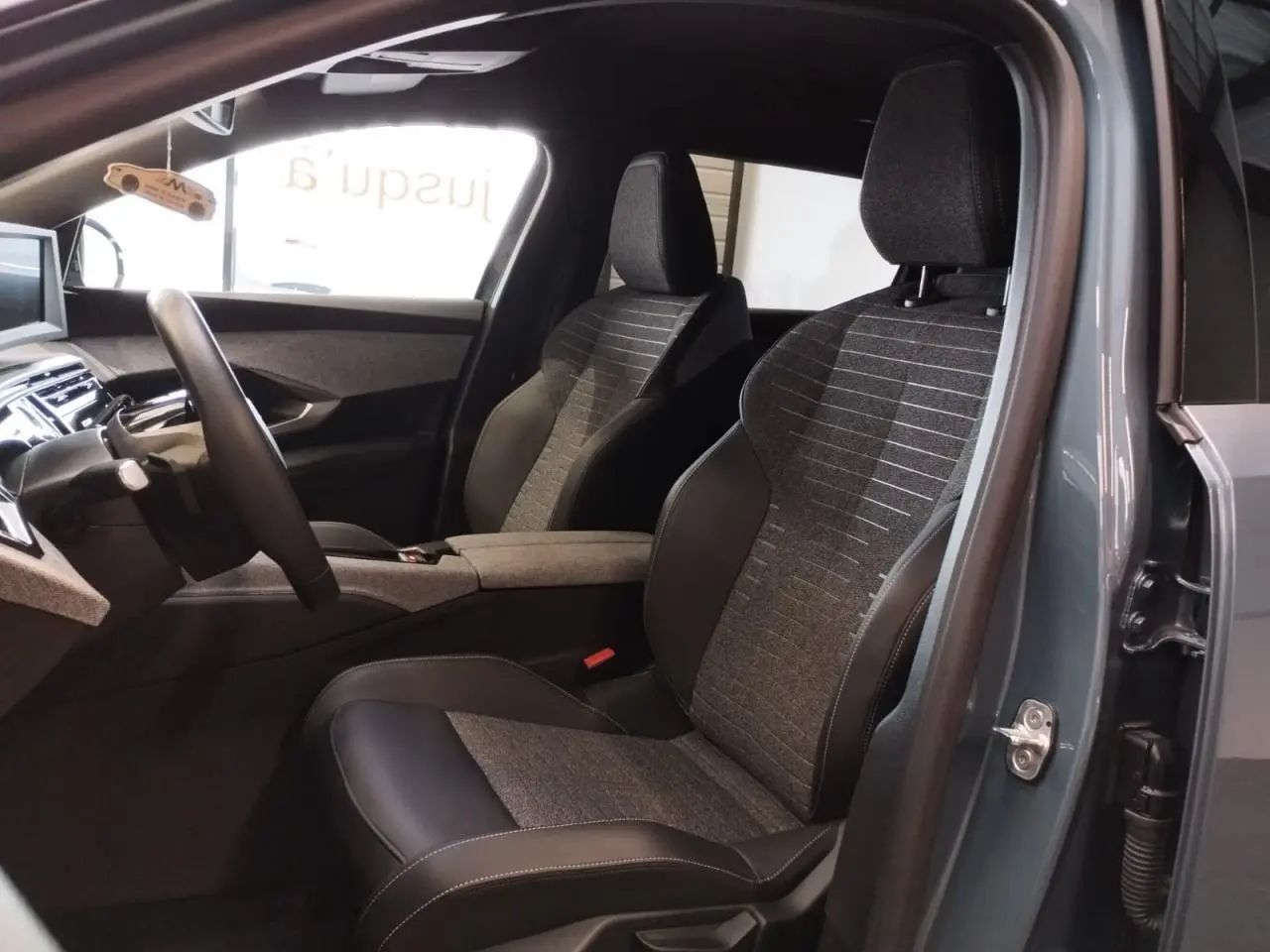 Vue intérieure côté gauche du Peugeot 5008 2025 bleu Ingaro, sièges tissu et cuir avec planche de bord moderne.