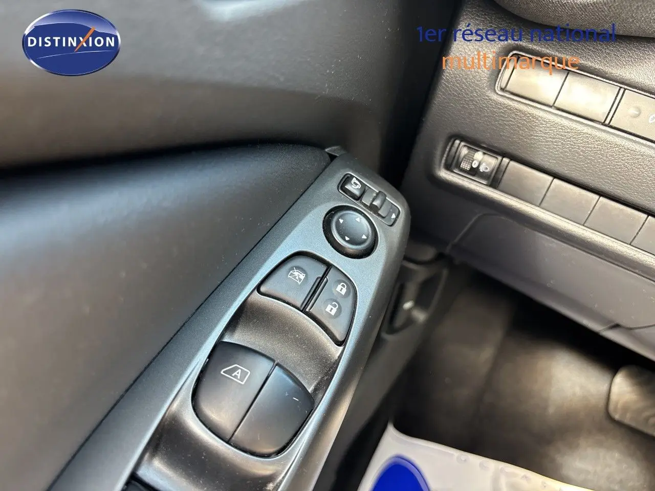 Détail des commandes de lève-vitres et rétroviseurs côté conducteur dans l’habitacle noir du Nissan Juke Hybrid 2024.