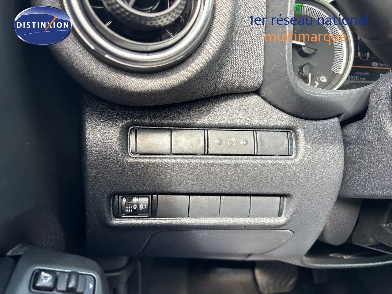 Détail intérieur du tableau de bord côté gauche du Nissan Juke gris, avec commandes de réglage d’éclairage et ventilation.