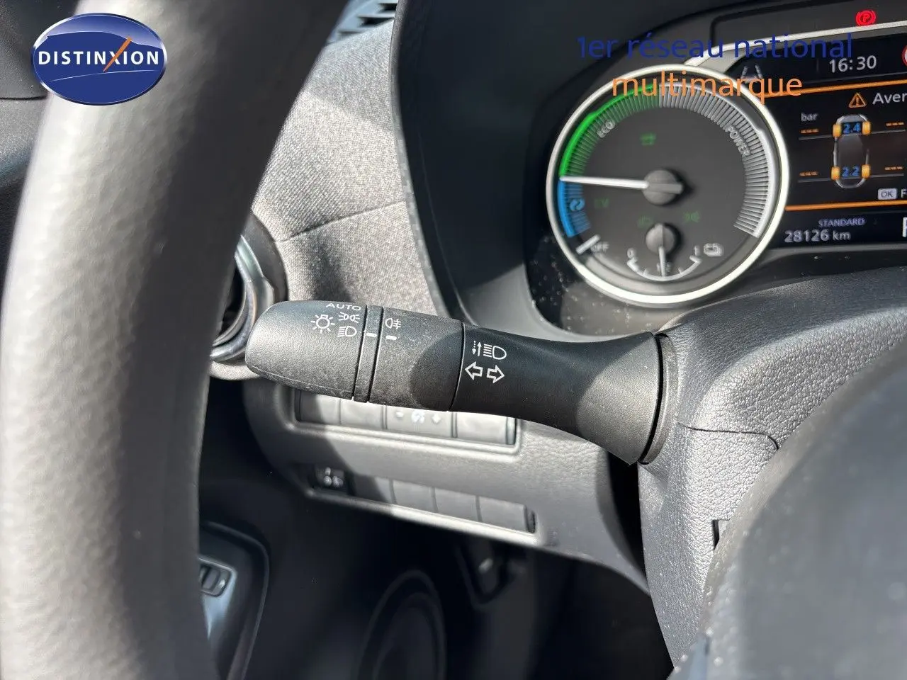 Gros plan sur la manette des clignotants à gauche du volant du Nissan Juke Hybrid 2024 avec tableau de bord numérique visible.