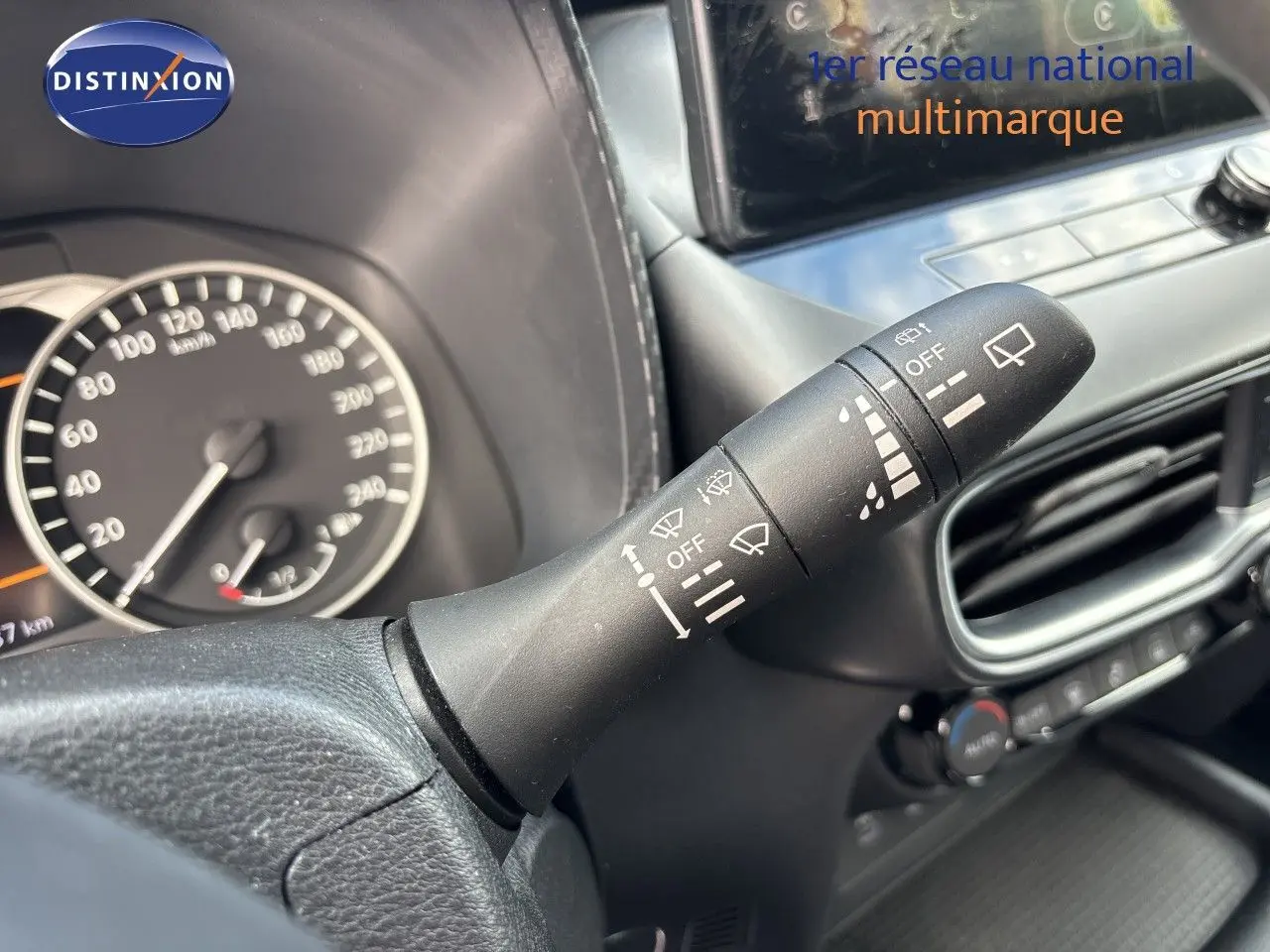 Gros plan sur la commande d’essuie-glace à droite du volant dans l’habitacle noir du Nissan Juke Hybrid 2024.