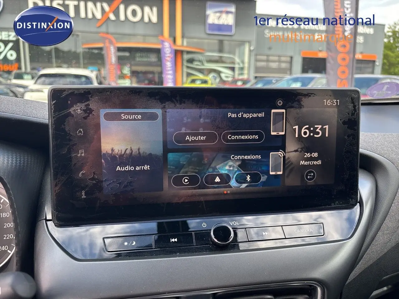 Écran tactile central du Nissan Juke hybride 2024 affichant les options de connexion et l'heure, intérieur gris.